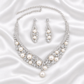Silver-tone pearl-style necklace and matching earrings on white satin